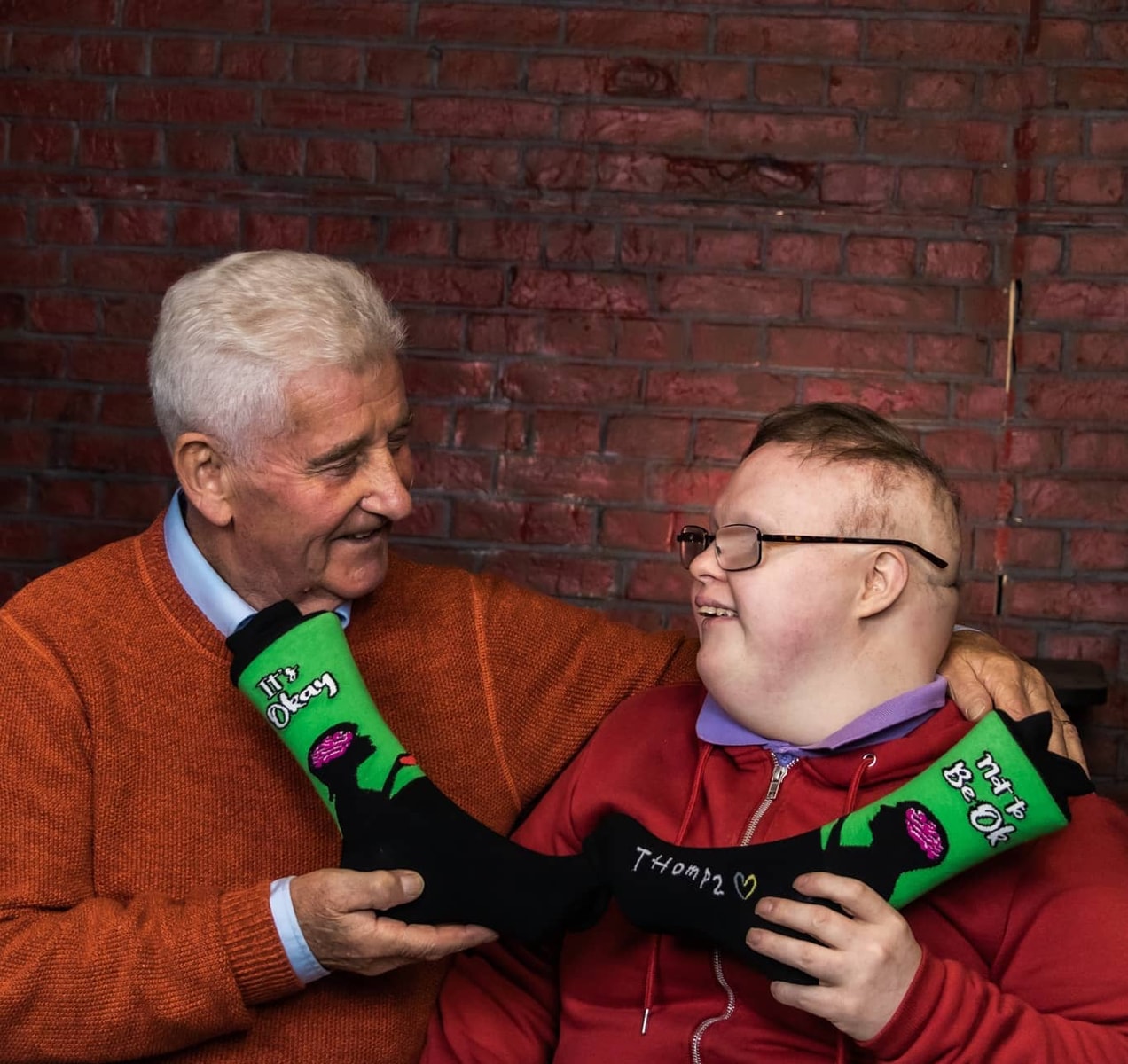 Thomas and his father with a pair of socks that say, 